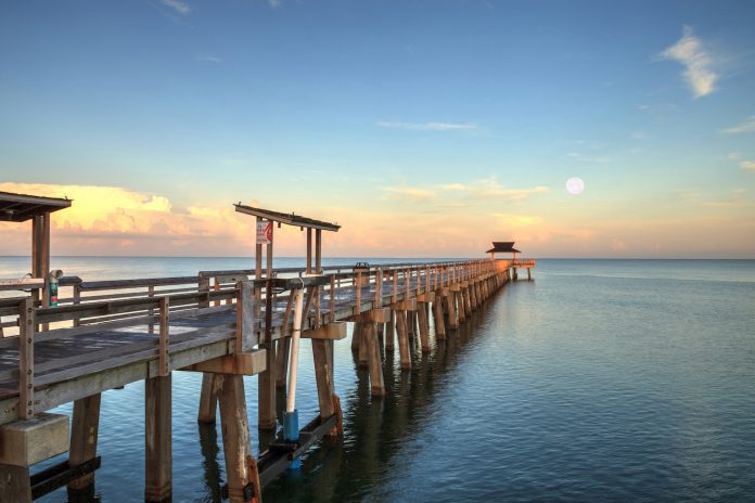 Moonset at Early sunrise over the Naples Pier on the Gulf Coast